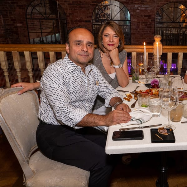 A man and woman seated at a table with drinks and appetizers at Darvish Kitchen.