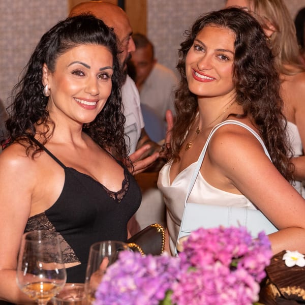 Two smiling women with dark curly hair at a lively Darvish Kitchen event.