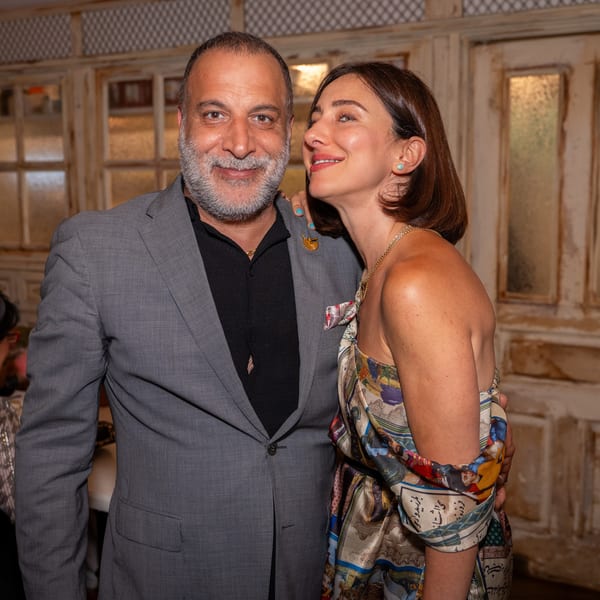 A smiling man with a beard and a woman in a patterned dress pose together at Darvish Kitchen.
