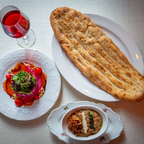 Middle-Eastern meal with flatbread, a red drink, a salad, and a dip with fried onions.