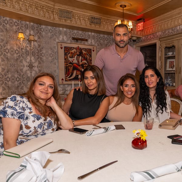 Five people, four women and one man, posing at a table in Darvish Kitchen, a middle-eastern restaurant.